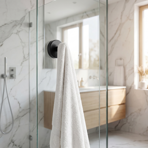 Livnorr matte black suction hook holding towel on marble bathroom wall