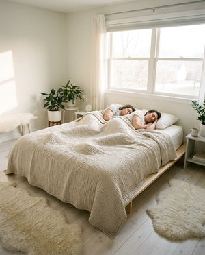 Couple sleeping under Livnorr muslin throw blanket in minimalist Scandinavian bedroom