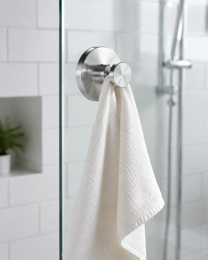 Brushed silver hook on glass shower door holding bath accessories