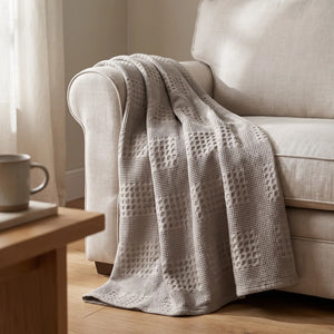 Waffle Weave Cotton Blanket draped over the arm of a linen sofa