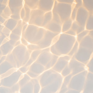 Shimmering water ripple light pattern on white wall